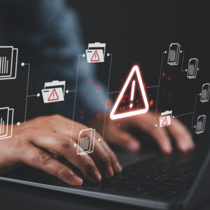 Warning alert icon with a hacked document system.Man typing on a keyboard with a red cybersecurity threat alert, surrounded by digital files and documents.